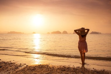 Bir şapka ve kısa elbise mutlu kadın'nde deniz günbatımı sahiptir. Denize, vintage renk arka plan dağlık karstik dağlarda