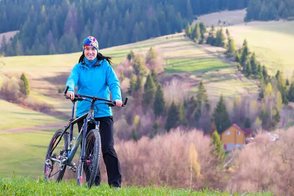Hermosa chica, ciclista de montaña en soleado día de primavera se encuentra en una zona montañosa en el bosque verde — Foto de Stock