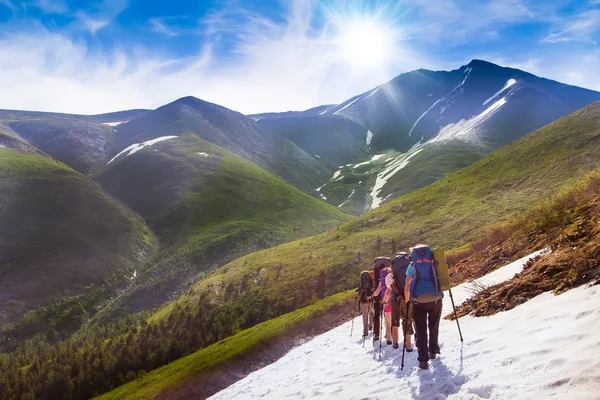 Grupo de amigos em caminhadas em altas montanhas. picos cobertos de neve, geleiras e Fantástico fundo do céu com nuvens azuis. Mundo bonito — Fotografia de Stock