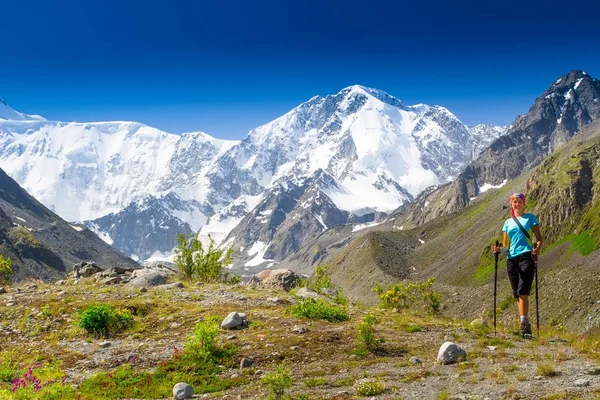 健康的女孩徒步旅行者登山杆克服困难在山区。高山，冰川的背景. — 图库照片