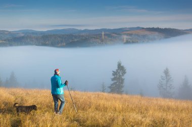 Bir köpek ile kız evden ayakta karşı bir Dağı Trekking kutup sabah sis ile devam ediyor. Manzara kompozisyon, arka plan dağlar ve gündoğumu.