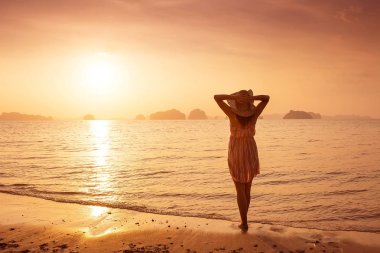 Bir şapka ve kısa elbise mutlu kadın'nde deniz günbatımı sahiptir. Denize, vintage renk arka plan dağlık karstik dağlarda