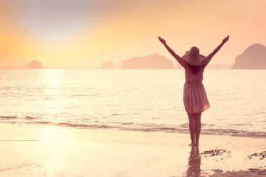 Bir şapka ve kısa elbise mutlu kadın'nde deniz günbatımı sahiptir. Denize, vintage renk arka plan dağlık karstik dağlarda