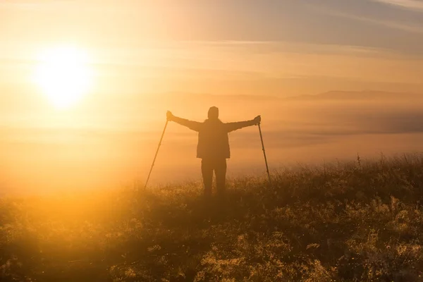 朝の霧で孤独なスポーツ トレッキング ポールを持つ少女のシルエット。景観の構成、背景の山々 と日の出. — ストック写真