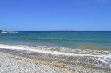 Girit 'teki Kato Gouves çakıl taşı plajı ve ufukta Dia adası görünüyor. Yunan adalarından biri.
