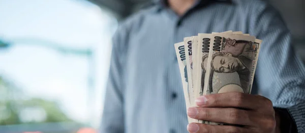 Empresario mano sosteniendo pila de billetes de yenes japoneses. negocios , —  Fotos de Stock