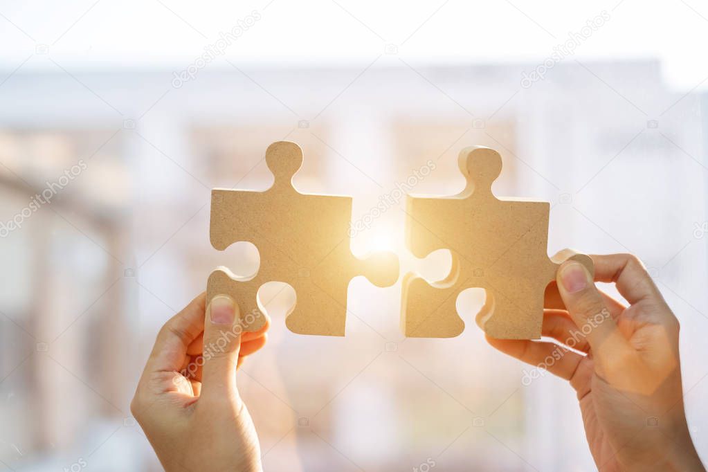Woman hands connecting couple puzzle piece against sunrise effec