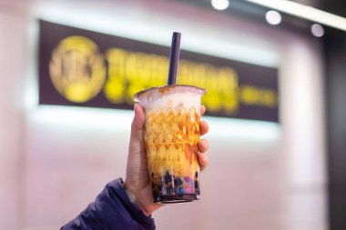 woman hand holding iced milk bubble tea with tapioca pearls and 