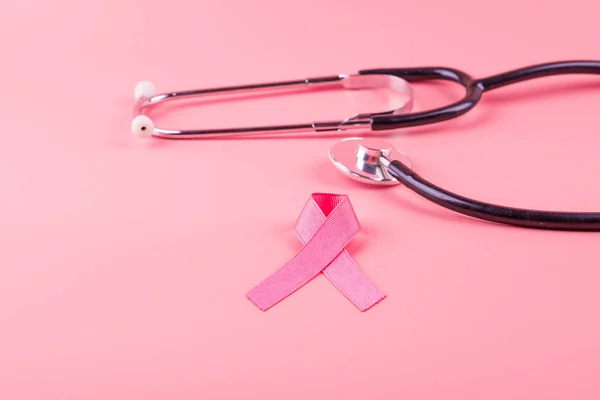 Осведомлённость о раке молочной железы, розовая лента со стетоскопом в качестве суппорта — стоковое фото