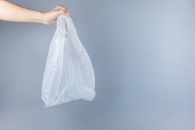 Gri arkaplana naylon torba tutan adam Boşluğu Kopyala 