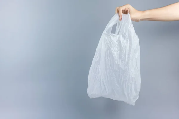 Homem segurando saco de plástico contra fundo cinza com espaço de cópia — Fotografia de Stock