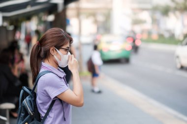 N95 solunum maskesi takan genç Asyalı kadın korumak ve filte