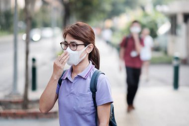 N95 solunum maskesi takan genç Asyalı kadın korumak ve filte