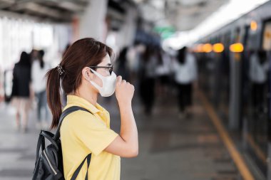 Genç Asyalı kadın Roman Coronavi 'ye karşı koruma maskesi takıyor.