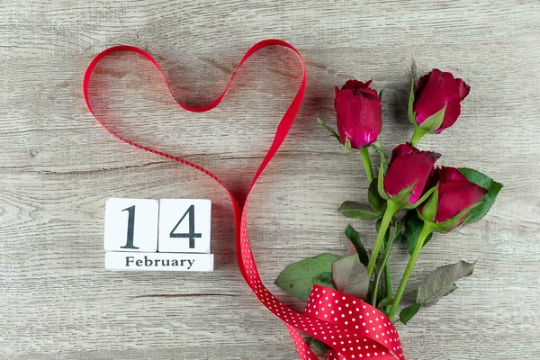 Piros rózsa virág és szív alakú szalag fa asztal háttér. — Stock Fotó