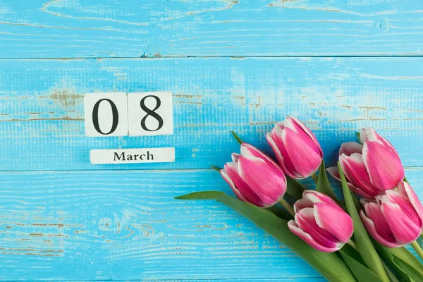 Flor de tulipa rosa e calendário de 8 de março na mesa de madeira azul de volta — Fotografia de Stock