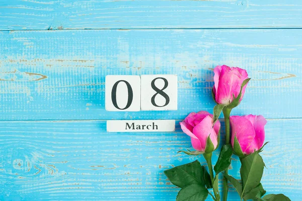 Roze roos bloem en 8 maart kalender op blauwe houten tafel backg — Stockfoto