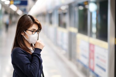 Kamu tren istasyonunda Roman Coronavirüs veya Corona Virüsü 'ne karşı koruma maskesi takan genç Asyalı bir kadın, solunum yolu enfeksiyonuna yol açan bulaşıcı bir virüstür.