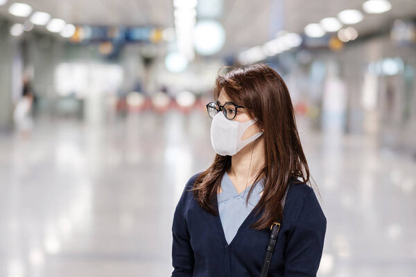 young Asian woman wearing protection mask against Novel coronavirus or Corona Virus Disease (Covid-19) at airport, is a contagious virus that causes respiratory infection.Healthcare concept