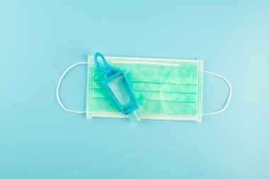 Novel coronavirus veya Corona Virüs Hastalığı (Covid-19) için cerrahi yüz maskesi ve el dezenfektanı jel dağıtıcısı mavi arka planda. Antiseptik, Hijyen ve Sağlık Konsepti