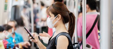 Metroda, Novel Coronavirus veya Corona Virüs Hastalığı (Covid-19) için cerrahi yüz maskesi takan genç bir Asyalı kadın var. Hijyen, Sağlık ve Enfeksiyon Konsepti