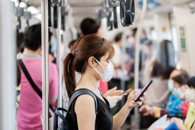 Metroda, Novel Coronavirus veya Corona Virüs Hastalığı (Covid-19) için cerrahi yüz maskesi takan genç bir Asyalı kadın var. Hijyen, Sağlık ve Enfeksiyon Konsepti