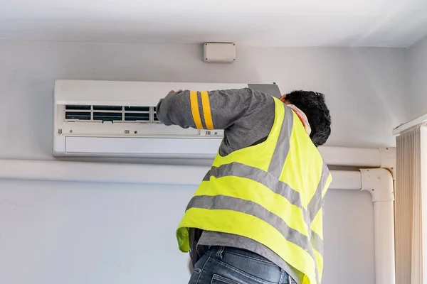 Young Man technician maintenance air conditioner indoors. Cleaning, Washing and Conditioning Service concept