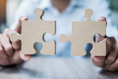 Adam çift bulmacasını masaya uzatıyor, işadamı ofis içinde tahta yapboz tutuyor. İş çözümleri, görev, hedef, başarı, hedefler ve strateji kavramları