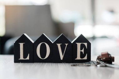 Ahşap ev modeli ve masa ofisinin anahtarı olan aşk metni. Yeni Ev, Finansal, Gayrimenkul Sevgililer Günü ve Gayrimenkul Konseptleri