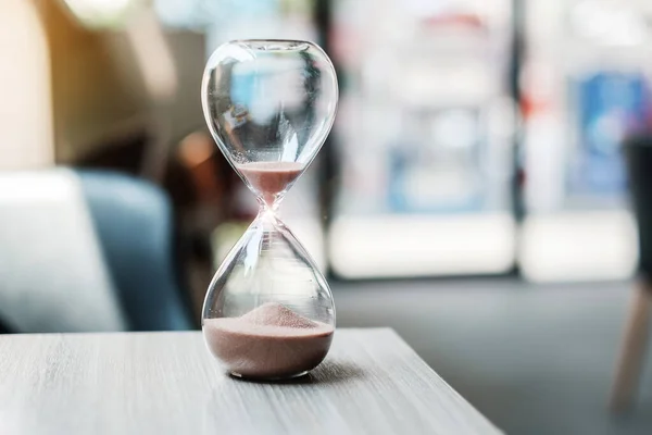 Hourglass on table office with copy space, Sand flowing through the bulb of Sandglass measuring the passing time. countdown, deadline, Life time and Retirement concept