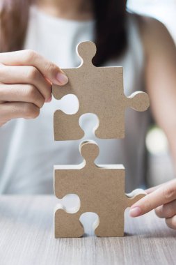 Kadın, çift bulmacasını masaya uzatıyor. İş kadını, ofis içinde tahta yapboz tutuyor. İş çözümleri, görev, hedef, başarı, hedefler ve strateji kavramları