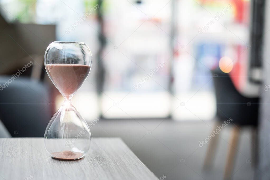 Hourglass on table office with copy space, Sand flowing through the bulb of Sandglass measuring the passing time. countdown, deadline, Life time and Retirement concept