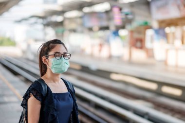 Devlet tren istasyonunda Novel Coronavirus ya da Corona Virüs Hastalığı 'na (Covid-19) karşı cerrahi maske takan genç Asyalı kadın. Hijyen, Sağlık ve Enfeksiyon Konsepti