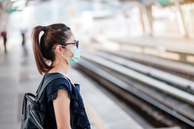 Devlet tren istasyonunda Novel Coronavirus ya da Corona Virüs Hastalığı 'na (Covid-19) karşı cerrahi maske takan genç Asyalı kadın. Hijyen, Sağlık ve Enfeksiyon Konsepti