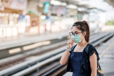 Devlet tren istasyonunda Novel Coronavirus ya da Corona Virüs Hastalığı 'na (Covid-19) karşı cerrahi maske takan genç Asyalı kadın. Hijyen, Sağlık ve Enfeksiyon Konsepti