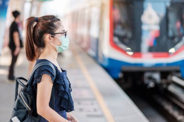 Devlet tren istasyonunda Novel Coronavirus ya da Corona Virüs Hastalığı 'na (Covid-19) karşı cerrahi maske takan genç Asyalı kadın. Hijyen, Sağlık ve Enfeksiyon Konsepti