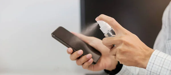 Man Hand Spuiten Alcohol Ontsmettingsmiddel Fles Naar Smartphone Tegen Novel — Stockfoto