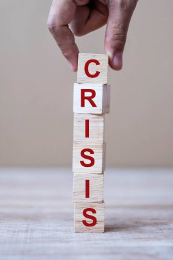 İş adamı masa arkasında CRISIS metni olan tahta küp bloklar düzenler. Coronavirus salgını, risk, düşüş İş dünyası, işsizlik, ekonomik durgunluk ve iflas kavramı