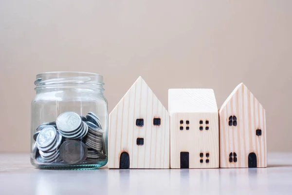 硬币放在玻璃瓶中 木制房屋模型放在桌子背景上 房地产和退休计划概念 — 图库照片