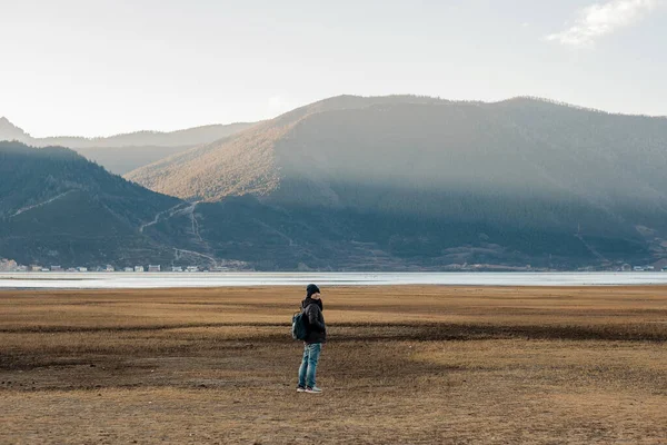 Hipster woman traveler with sweater and backpack traveling at Napa Lake, Happy young Hiker looking mountain and sunset in trip Shangri-La,Yunnan,China. Explore, Adventure and Asia Solo travel concept