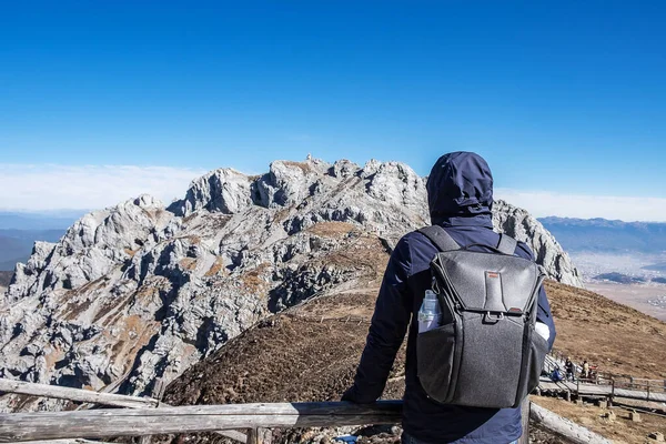 Young man traveler traveling at Shika Snow Mountain or Blue Moon Valley, landmark and popular for tourists attractions in Zhongdian city (Shangri-La). Yunnan, China. Asia and Solo travel concept