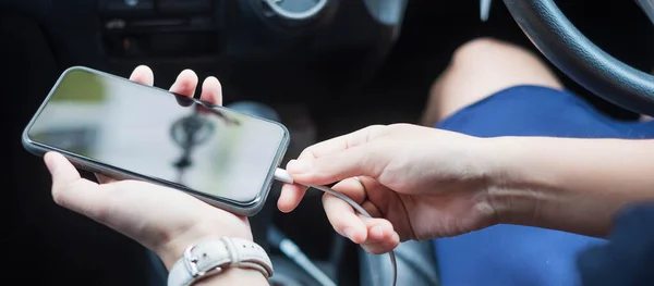 Woman charging smartphone in car. Technology and transportation concepts