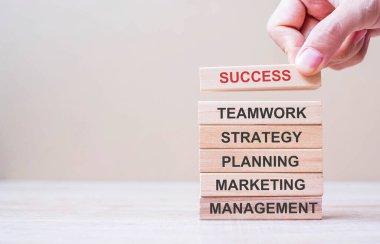 İş adamının elle kuleye tahta bloğu metin ile yerleştirmesi veya çekmesi; Başarı, Takım Çalışması, Strateji, Planlama, Pazarlama ve Yönetim. İş kavramları