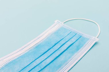 Mavi arka planda tıbbi maske. Kirliliğe, virüse, gribe, öksürüğe ve korona 'ya karşı güvenlik maskesi.