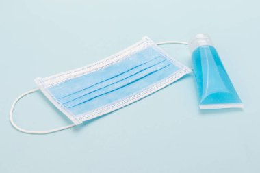Sağlık maskesi ve el dezenfektanı jeli mavi zemin üzerinde hijyen koronası virüsü koruması için