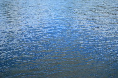 Su yüzeyinde dalgalanmalar ve güneş ışınları yansımaları