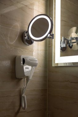 Işıklı aynalar ve lüks taş duvarda bir el kurutma makinesi. 
