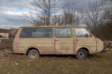 Diğer arabalardan yapılmış terk edilmiş paslı araba yol kenarında duruyor..
