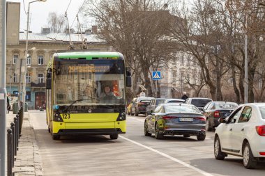 Lviv, Ukrayna - 03-01-2020: Modern Trolleybus - Ukrayna 'da yaygın olarak kullanılan elektrik nakliyesi - güneşli bir günde yol kenarına park edilmiş arabalarla şehrin bir caddesinde.