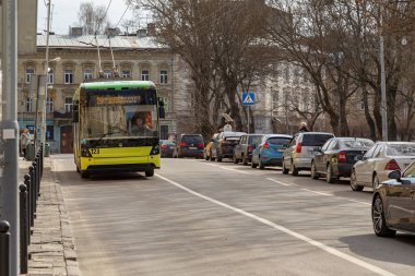 Lviv, Ukrayna - 03-01-2020: Modern Trolleybus - Ukrayna 'da yaygın olarak kullanılan elektrik nakliyesi - güneşli bir günde yol kenarına park edilmiş arabalarla şehrin bir caddesinde.